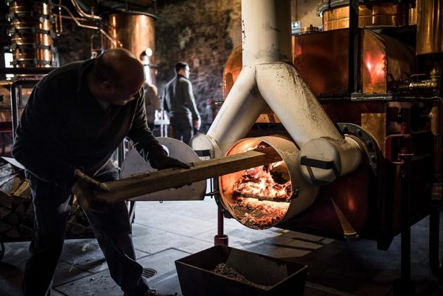 A distiller stokes the fire underneath the column in a wood-fired, continuous-run, pot still at Chateau du Tari-quet