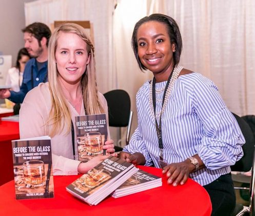 Author Heather Dolland, right, talks with Lacie Thornton, of Grand Traverse Distillery, during a book signing at the White Mule Press booth.