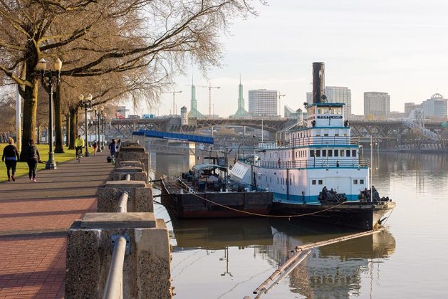 The twin towers of the Oregon Convention Center, site of the 2018 ADI Conference, break the Portland skyline behind the Sternwheeler Portland, which houses the Oregon Maritime Museum and is berthed along the Tom McCall Waterfront Park on the Willamette River.